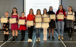 Young athletes posing with certificates on stage