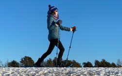 A woman using cross country ski equipment in a snowy field, for the equipment lending program